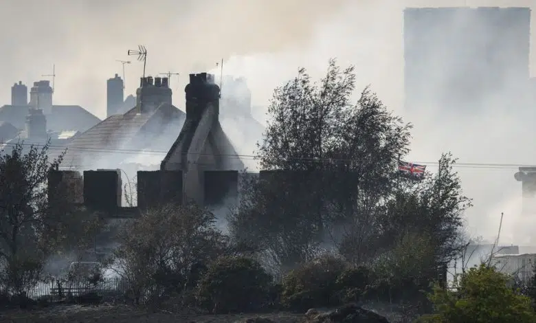 Los incendios forestales arden en Londres durante una ola de calor récord 1 A British flag flies amongst the smoldering ruins of houses as fire services tackle a large blaze on July 19 in Wennington, England. A series of grass fires broke out amid an intense heatwave.
