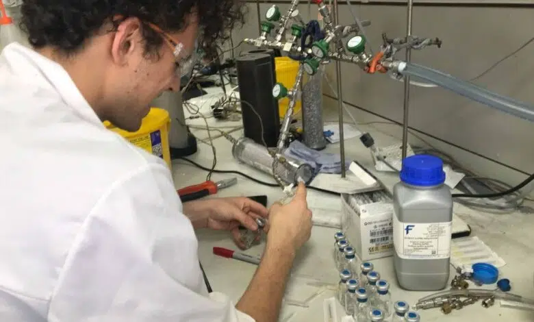 Los científicos descubren una antigua fuente de oxígeno que pudo haber alimentado la vida en la Tierra primitiva 1 Scientist in a lab coat is pictured injecting something into a small glass vial on a lab bench