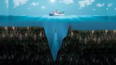 We see a boat on the water and a deep ocean trench below it.