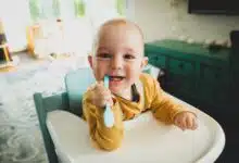 baby at highchair chewing on toothbrush