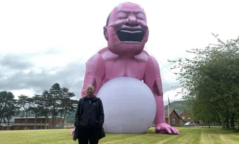 Un hombre gigante de color rosa ha causado revuelo en un pueblo de Gales. ¿Qué quiere decir esto? 1 Yue Minjun frente a su instalación de arte inflable (Escuela Lucin).